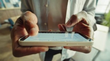 İş için akıllı telefon kullanan tanınmaz bir serbest çalışanın fotoğrafı. Afrika kökenli Amerikalı iş adamının elleri ekrandaki grafiklere ve istatistiklere bakıyor. Modern çağın bulanık arkaplanı