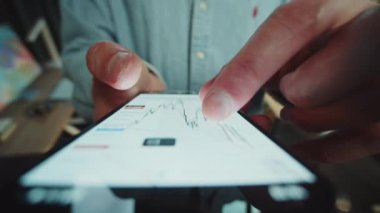 Marketi kontrol etmek için cep telefonuyla ön taraftan ateş edilmiş. Dokunmatik ekran aygıtının pazar grafiği kaydırılıyor. İş dünyası