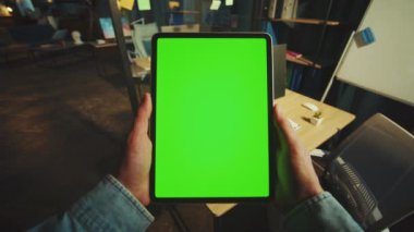 Ofisinde yeşil ekran olan dikey tablet bir bilgisayarı tutan elleri kapat. Model ekran. Cihaz. Daire