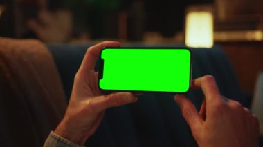 Koltukta uzanan yatay yeşil ekranlı bir cep telefonunda daktilo kullanarak ellerini kapat. Sosyal medya. Akıllı telefonmuş. Model