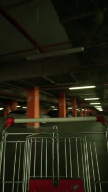 Metalik alışveriş arabasının yeraltı otoparkında insan olmadan dolaşması. Endüstriyel iç