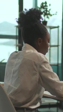 Sandalyede oturan çekici Afro-Amerikalı iş kadını dizüstü bilgisayarını ofisinde işine yoğunlaştır. Ciddi görün. Kamera hareket ediyor. 360 derece