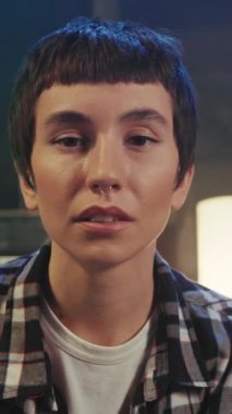 Modern konforlu oturma odasındaki kanepede otururken kısa saçlı, doğrudan kameraya bakan beyaz bir kadının portresi. Şehir tarzı. Kapalı