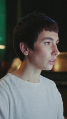 Kendine güvenen, kısa saçlı, bilgisayar başında oturan ve geceleri modern çatı katında çalışan genç bir kadının görüntüleri. Kameraya bakan çekici, modaya uygun bir kızın portresi. Kapalı