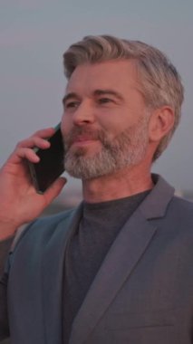 Çekici, mutlu iş adamı cep telefonuyla konuşur ya da gökdelenin çatısındaki akıllı telefonla konuşur. Yavaş çekim