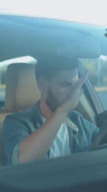 Bakımlı sakallı bir adam araba sürmeye odaklanıyor, modern bir iç ve yol güvenliğini ön plana çıkarıyor.