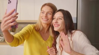 İki mutlu evli lezbiyen selfie çekiyor ve evde kameraya yüzükler gösteriyor.