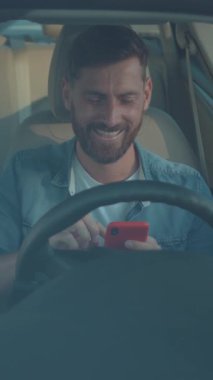 Şen şakrak bir adam şehirde araba sürerken akıllı telefonuyla meşgul oluyor, modern bağlantılarını gösteriyor.