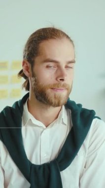 Bu ilgi çekici videoda, yeşil kazaklı sakallı bir adam kamerayla neşeyle etkileşime geçiyor, sıcaklığı ve arkadaşlığı uzun saçlarıyla ve bulaşıcı gülümsemesiyle yayıyor.