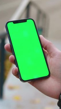 Bir kişi elinde parlak yeşil ekranlı akıllı bir telefon tutuyor. Uygulama ve tasarım modellemeleri için mükemmel.