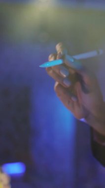 Parlak ve canlı, bulanık ışıklarla çevrili mavi bir kalemi sıkıca kavrayan bir elin yakından görüntüsü.