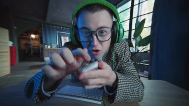 Gözlüklü ve kulaklıklı komik adam bilgisayar faresi kullanıyor. Oynayın. Aktif adam. Ofis ya da daire