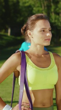 Canlı spor kıyafetleri içinde fit ve hevesli bir kadın spor bantlarıyla açık hava aktivitelerine hazır.