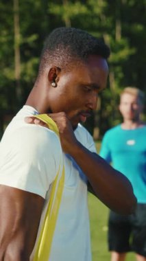 Bir atlet direnç bandını etkin bir şekilde hem esnemek hem de güneşli bir ortamda antrenman yapmak için kullanıyor.