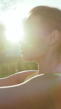 Güzel ve huzurlu bir an, dışarıda yoga yapan bir kadının sıcak güneş ışığında zarif bir şekilde yıkandığını gösteriyor.