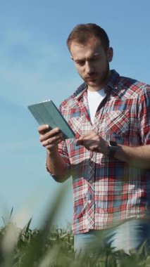 Odaklanmış bir adam tabletiyle verimli yeşil bir alanda etkileşime girer ve modern teknolojiyi doğada sergiler..