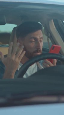 Araba sürerken telefonla konuşan, dikkati dağılmış sürüş davranışlarını gösteren bir adam..