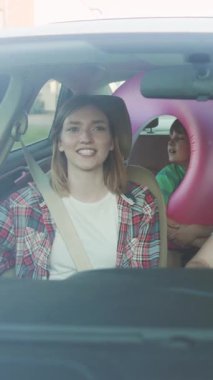 Neşeli bir anne çocuklarını arabayla götürüyor, unutulmaz bir aile yolculuğunun tadını çıkarıyor.