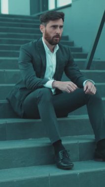 Sivri takım elbiseli bir işadamı zarif adımlarla düşüncelere dalmış modern estetiği somutlaştırıyor.