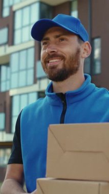 Mavi yelekli neşeli bir teslimatçı, iş gününü karton kutularla geçiriyor. Pozitif tavır sergiliyor ve görevlerine bağlılığını gösteriyor.