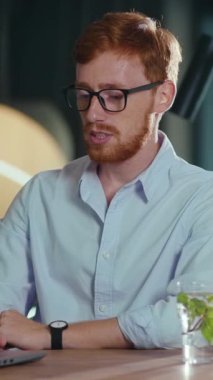 Videoda dizüstü bilgisayarlı bir masada üç kişi gözlüklü sakallı, çarpıcı kızıl saçlı bir adam ve bir diğeri de teknik çalışma alanında çeşitlilik gösteren gözlüklü bir adam var.