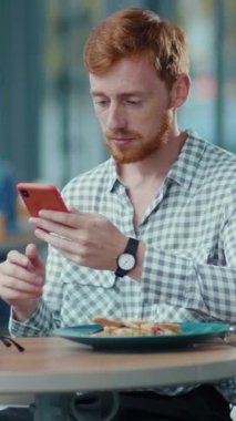 Masadaki bir adam yemek tabağını görmezden gelerek cep telefonuyla meşgul oluyor. Bu sahne modern teknoloji ve günlük yaşamın çatışmasını vurgular.