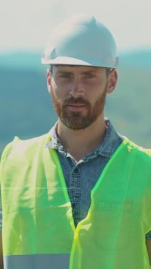 Videoda kendine güveni tam bir adam, sarı güvenlik yeleği giyiyor, endüstriyel işler ve güvenliği gösteriyor ve liderlik için kollarını kavuşturuyor.