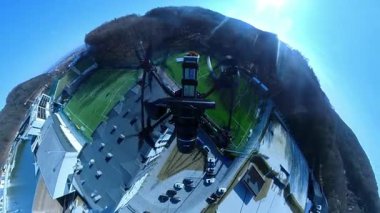 Göl ve ağaçlarla doğa arka planında uçan akıllı helikopter cihazı. Muhteşem tatil köyünün havadan görünüşü. Optik yanılsama. Havada uçan kamerayla donatılmış insansız hava aracı. Güneşli bir gün