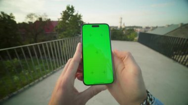 Sosyal medyayı dışarı kaydırırken erkeklerin cep telefonlarını maket ve yeşil ekranla tutarken yakın plan çekimleri. Akşam parkında akıllı telefondan gelen mesajlara cevap veren tanınmayan bir adam.