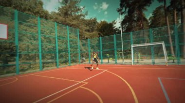 Canlı bir şehir parkında basketbol ve futbol aktivitelerinin yer aldığı enerjik açık hava spor ortamı.