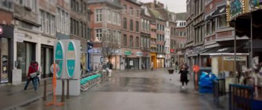 Yağmurlu bir günde yakalanan sakin bir şehir caddesi, çeşitli büyüleyici dükkanları ve park edilmiş bisikletleri ön plana çıkarıyor.