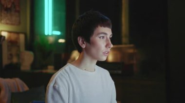 Kendine güvenen, kısa saçlı, bilgisayar başında oturan ve geceleri modern çatı katında çalışan genç bir kadının görüntüleri. Kameraya bakan çekici, modaya uygun bir kızın portresi. Kapalı