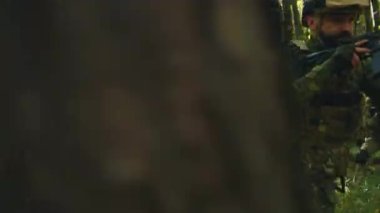 Silahlı erkek ve kadın askerlerin taktik harekat sırasında ormanda hareket ettikleri görüntüler. Savaş konsepti. Silahlı kuvvetlerin eğitimi. Uluslararası ortaklık. Açık havada. Gündüz vakti. Sonbahar. Tabur.