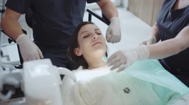 Dişçi koltuğunda uzanan beyaz kadın hasta. Mavi üniformalı hemşire klinikte dişçi önlüğü takıyor. Sağlık sigortası konsepti. Stomatoloji. Kapalı