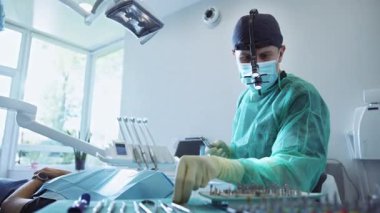 Modern dişçi aletleri ve ekipmanları kullanarak hastayı ameliyat eden iki sağlık çalışanı. Diş ameliyatı. Tıp, sağlık hizmetleri konsepti. İçeride. Stomatoloji. Klinikteki diş muayenehanesi