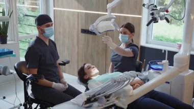 Hafif klinik asistanları ve tıbbi maskeli erkek dişçiler diş tedavisi için diş aletlerini tutarlar. Hydience ve sağlıklı.