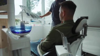 Adam dişçi koltuğunda oturuyor. Diş hekimi diş tedavisine başlayan bir diş aleti tutuyor. Hydience ve sağlık. Modern klinik