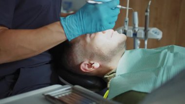 Hasta dişçi koltuğunda oturuyor. Dişçi dişleri tedavi eden bir diş aletini tutuyor. Hydience ve sağlık. Modern klinik.