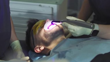 Dişleri tedavi eden hastayı kapatın. Eller dişçi ve asistanlar diş aletini tutuyor. Hydience ve sağlıklı. Modern klinik