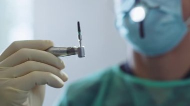 Tıbbi maskeli diş hekimi modern klinikte diş aletini tutuyor. Hydience ve sağlıklı.