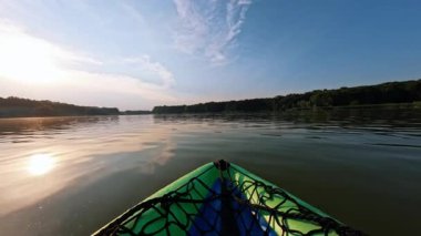 Yazın akşamları gölde kayak yapmak. Sakin ol, sakin ol, sakin ol. Gün batımında kano. Açık havada. Arka planda güzel bir doğa. Aktif hafta sonu. Su sporu, aktiviteler