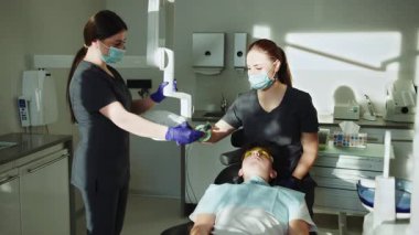 Hafif klinikteki kadın dişçi ve tıbbi maskeli asistan dişleri tedavi eden diş aletlerini tutuyor. Hydience ve sağlıklı.
