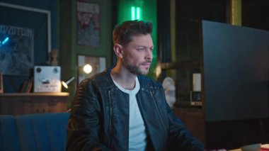 Bilgisayarda çalışan üzgün bir adamın görüntüsü. Yorgun adam içerideki monitöre bakıyor. Kötü gün konsepti. Arka planda bulanık neon ışığı. Baş ağrısı