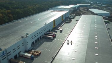 Geniş, modern bir depo ve dağıtım merkezinin etkileyici ölçeklerini ve tasarımlarını gösteren yüksek açılı bir bakış açısı.