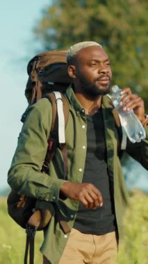 Bir adam, büyük bir sırt çantası ve ferahlatıcı suyla güzel bir açık havanın tadını çıkarıyor. İlerideki macerasına hazır.