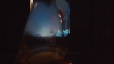 Beyaz laboratuvar önlüklü sakallı bilim adamının buzdolabından test tüpü alırken çekilmiş fotoğrafı. Tıp merkezinin laboratuarında buzdolabının yanında duran genç bir araştırmacı. Akşam içeride.