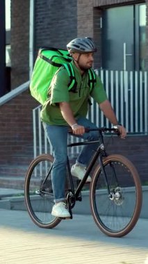 Teslimat teçhizatı olan bir bisikletçi işlek bir şehir caddesinde modern şehir teslimat trendlerini sergiliyor.