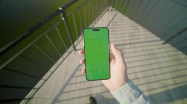 Genç adam elleri yeşil ekran ile dikey telefon tutuyor. Arka planda güzel bir göl. Doğa. Akıllı telefondan yazıyorum.