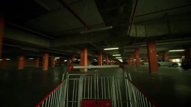 Metalik alışveriş arabasının yeraltı otoparkında insan olmadan dolaşması. Endüstriyel iç
