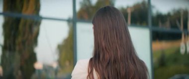 Akıllı telefonu elinde tutan ve sohbet eden güzel bir genç kadının yatay görüntüsü. Dinlenme merkezindeki gülümseyen kızın portresi. Arka plan bulanık. Gündüz vakti. Açık havada.